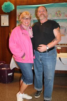 A couple pose in front of a banner.