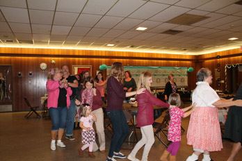 Dancers of all ages form a conga line.