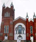 First Presbyterian Church, a red brick building with a nave flanked by two different-sized towers